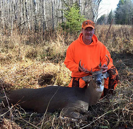 Deer hunter in blaze orange with his buck